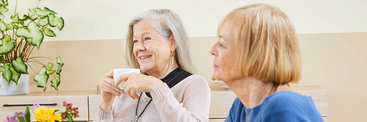 Zwei ältere Damen sitzen an einem Tisch bei einer Kaffeejause.
