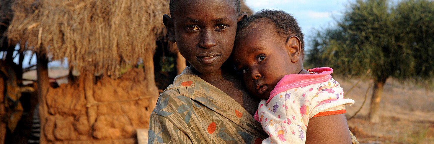 Mädchen mit Kleinkind auf dem Arm in Kenia