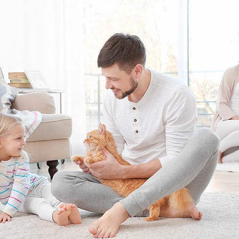 Familie mit 2 kleinen Kindern spielt am Boden