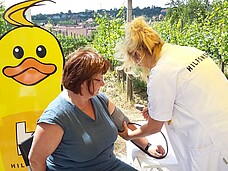 Eine Pflegefachkraft misst einer Frau den Blutdruck