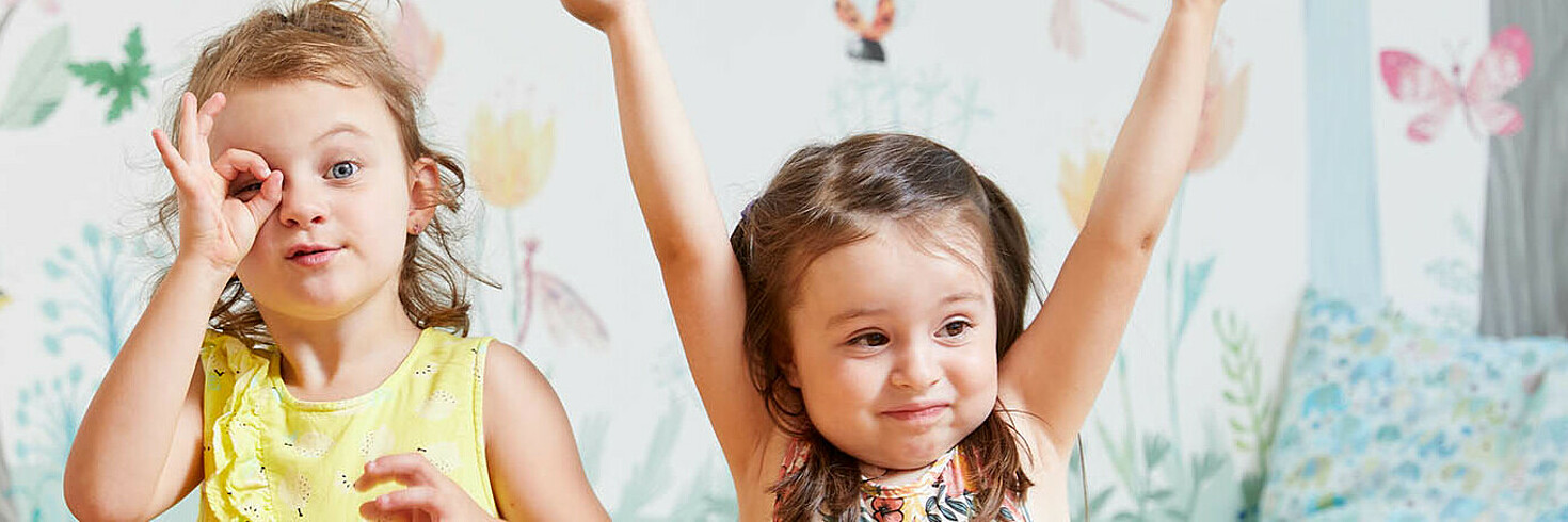 Drei Kinder im Vorschulalter formen mit den Händen ein Fernrohr und gucken durch