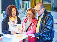 2 Damen und Othmar Karas stehen beim Informationsstand und reden. 