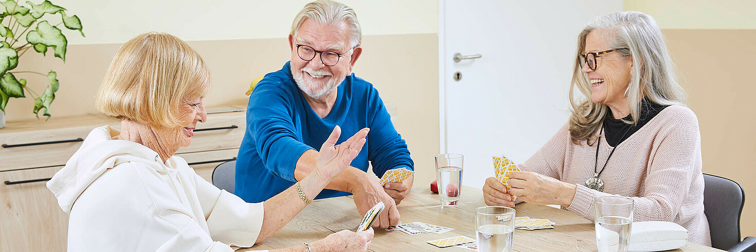Ein Mann und zwei Frauen haben Spaß beim Karten spielen.