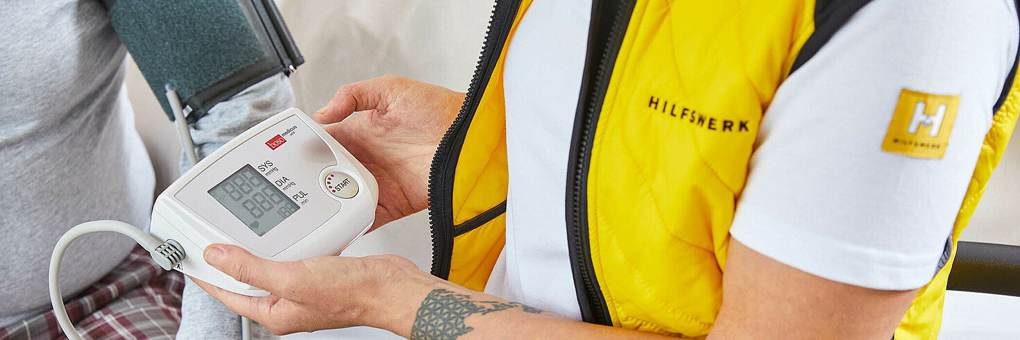 Eine Hilfswerk Mitarbeiterin mit Blutdruckmessgerät