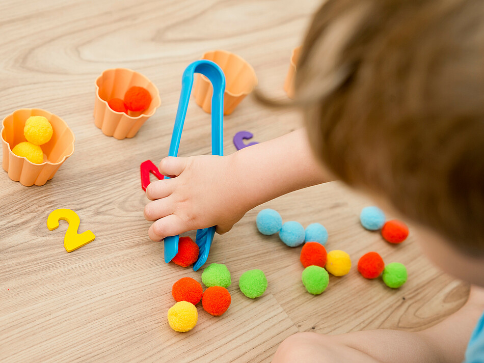 Kleinkind spielt mit Filzkugeln 