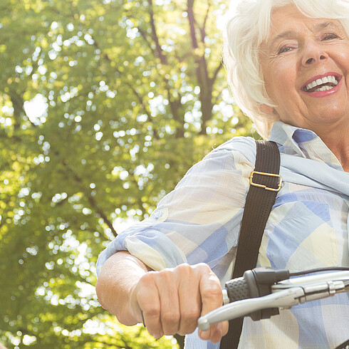 Ältere Frau in der Natur mit dem Fahrrad
