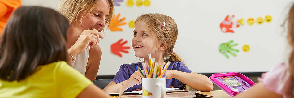  Mädchen im Volksschulalter werden von Freizeitpädagogin beim Lernen unterstützt