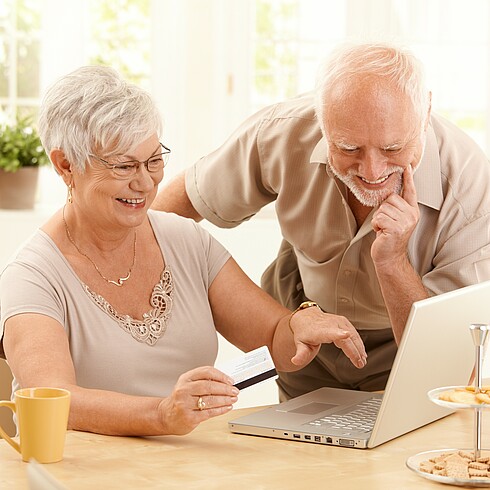 Ein älteres paar sieht auf einen Laptop.