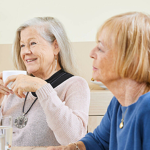 Zwei ältere Damen sitzen an einem Tisch bei einer Kaffeejause.