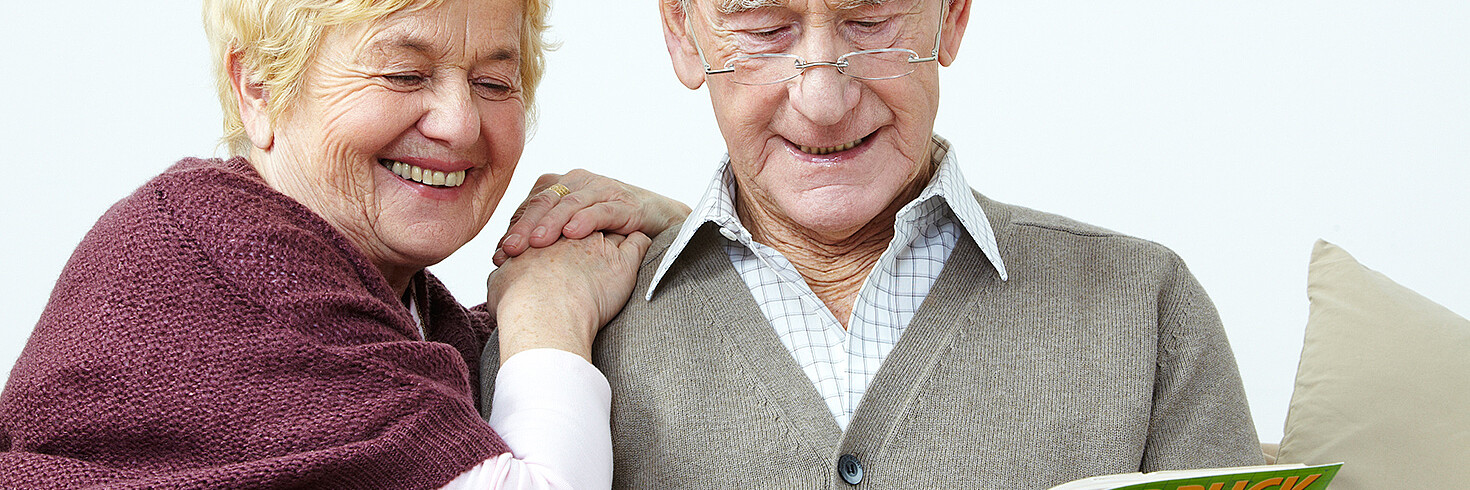 Seniorin und Senior sitzen und lesen gemeinsam