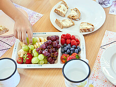 Nahaufnahme von Kinderhänden, die nach Früchten und Beeren greifen