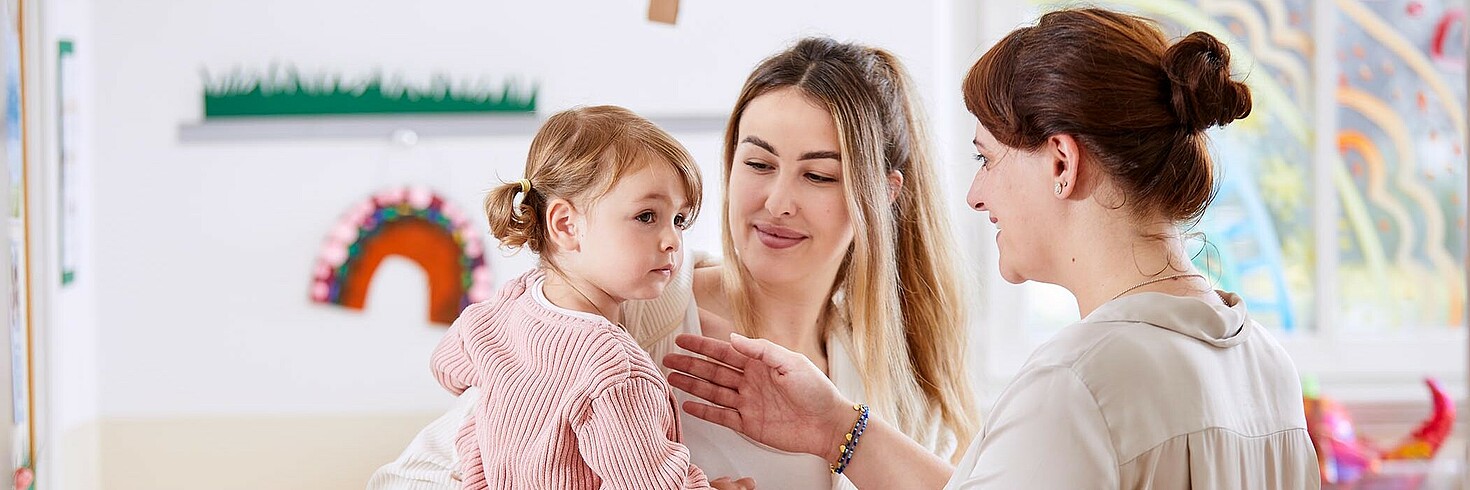 Mutter übergibt ihre Tochter in die Obhut der Kindergartenpädagogin