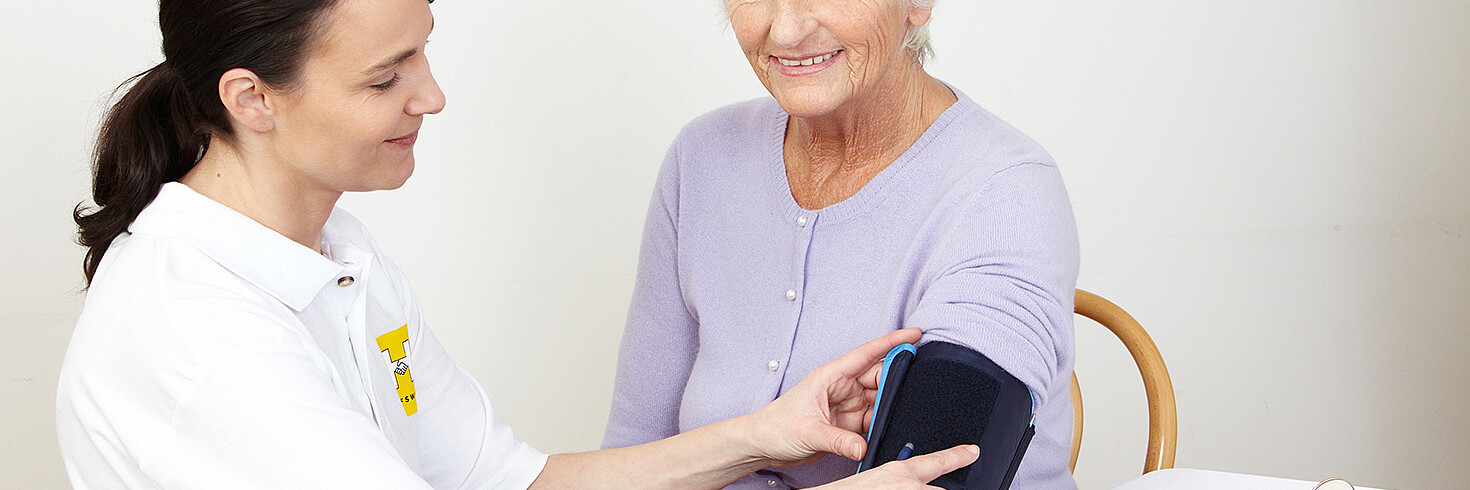 Pfleger misst bei einer älteren Damen den Blutdruck