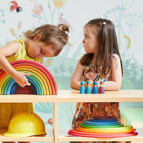 Drei Kinder im Vorschulalter spielen konzentriert mit bunten Holzspielzeug