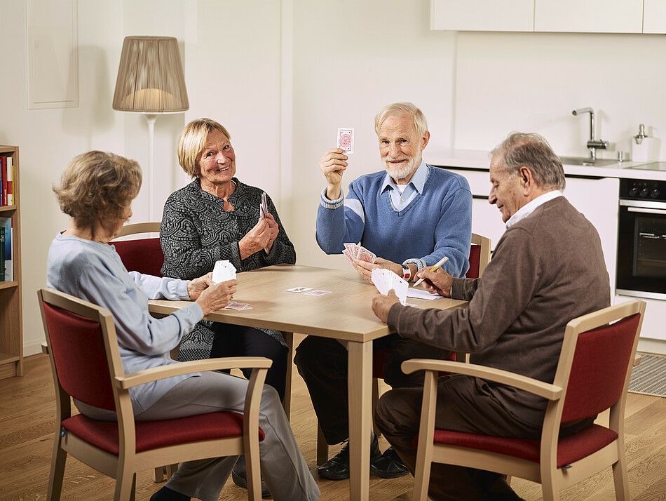 Zwei ältere Damen und zwei ältere Herren spielen Karten.