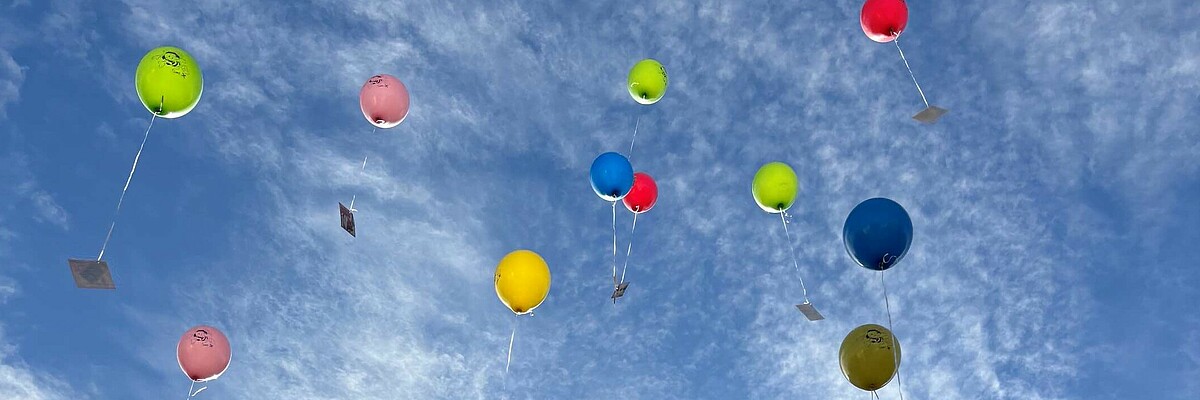 Bunte Ballons mit Botschaften steigen in den Himmel über Österreich.