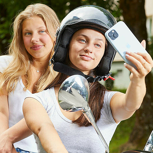 Zwei Jugendliche machen ein Selfie auf einem Scooter