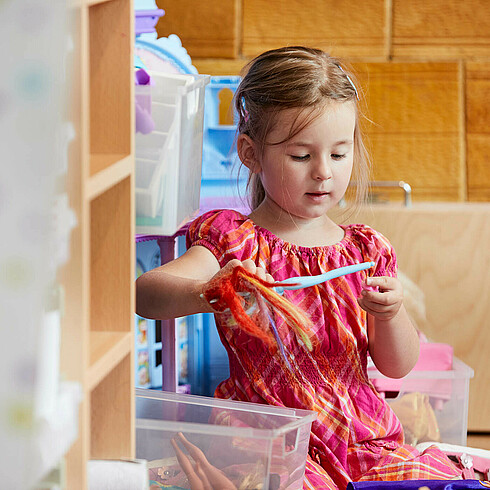 Mädchen im Vorschulalter spielt mit blauer Plastikpuppe