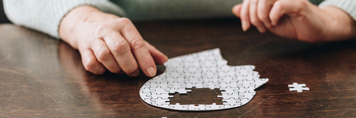 Puzzlesteine, die einen Kopf darstellen auf einem Tisch.