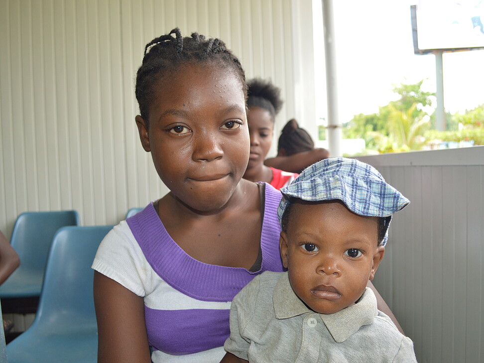 Mutter mit Kind am Schoß im Warteraum vom Krankenhaus in Haiti