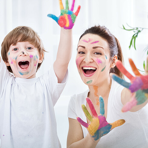 Mutter mit Kind mit Farbe im Gesicht und an den Händen