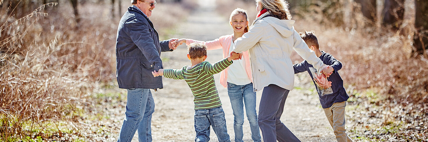 Großeltern laufen mit Kindern an der Hand im Kreis