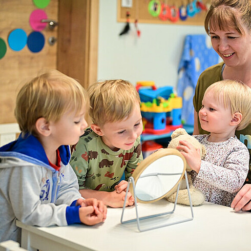 Drei Kinder spielen beim Tisch