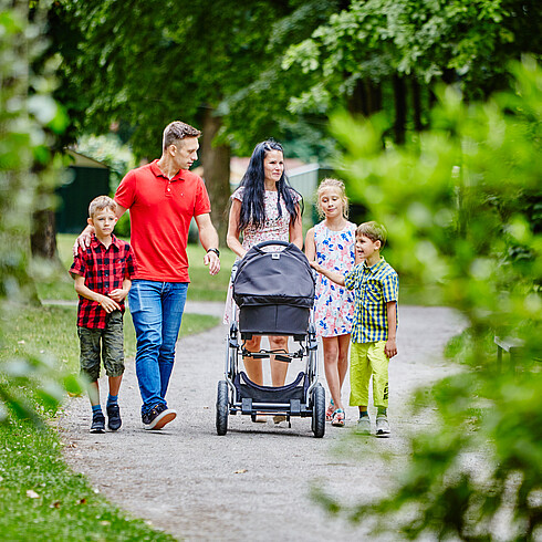 Familie spaziert mit ihren Kindern im Grünen