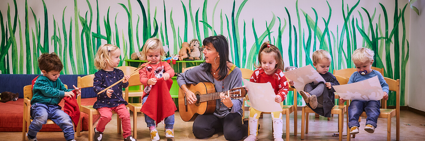 Kinder in der Gruppe singen zu Lied auf Gitarre