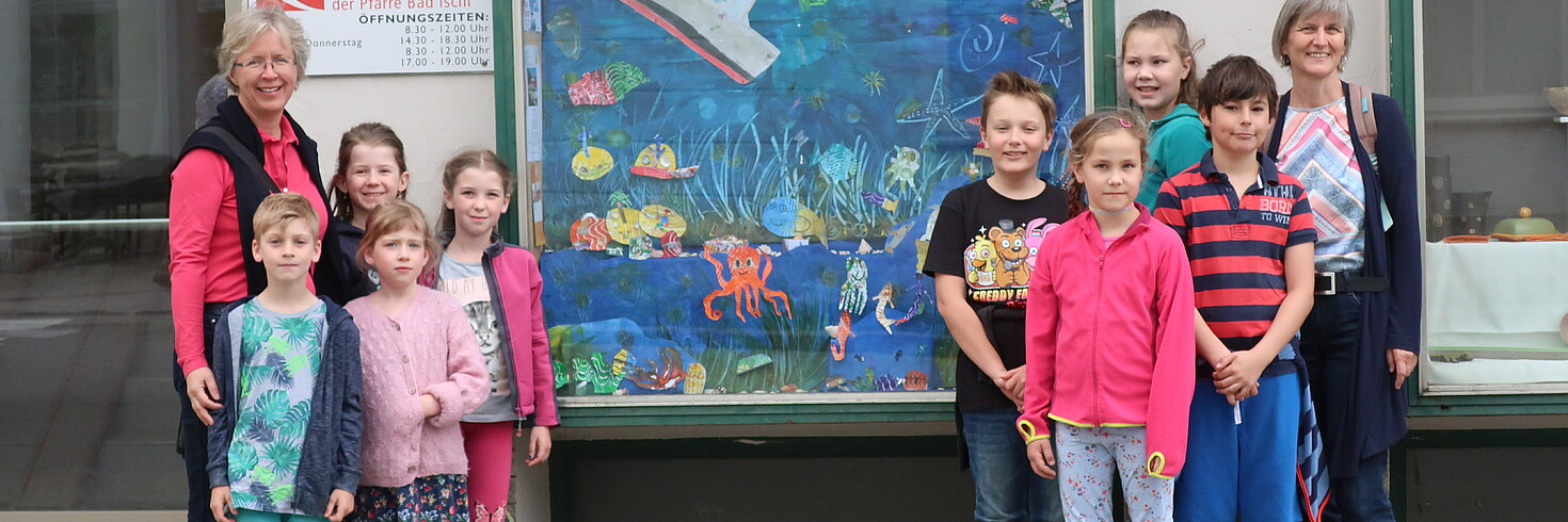 Kinder stehen mit ihre Lehrerinnen vor dem selbst gestalteten Schaufenster