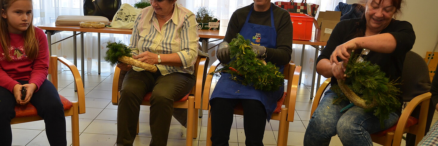 3 Damen und ein junges Mädchen sitzten in der Runde beim Binden