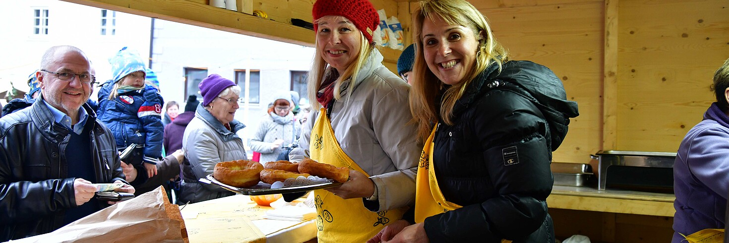 2 Damen stehen in einer Hütte und verkaufen Bauernkrapfen