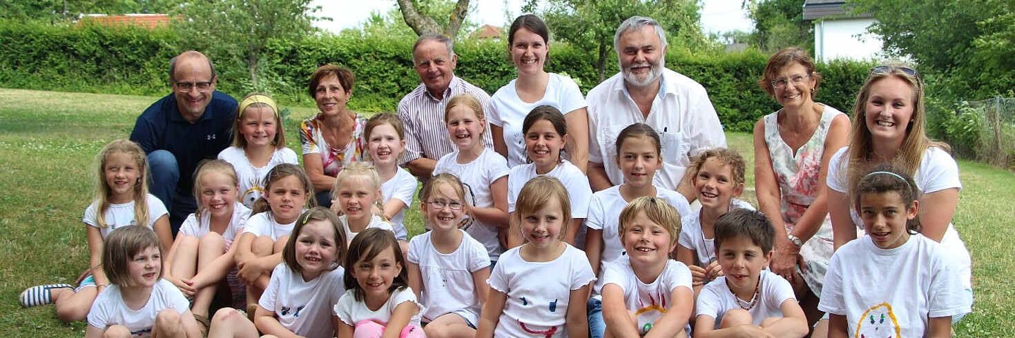 Kindergruppe und Erwachsene auf der Wiese vor dem Hort