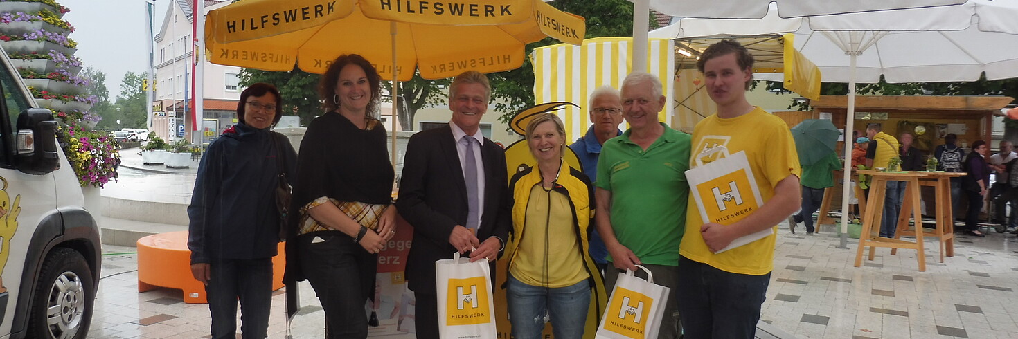 3 Damen und 4 Herren stehen unter einem Sonnenschirm des OÖ Hilfswerk