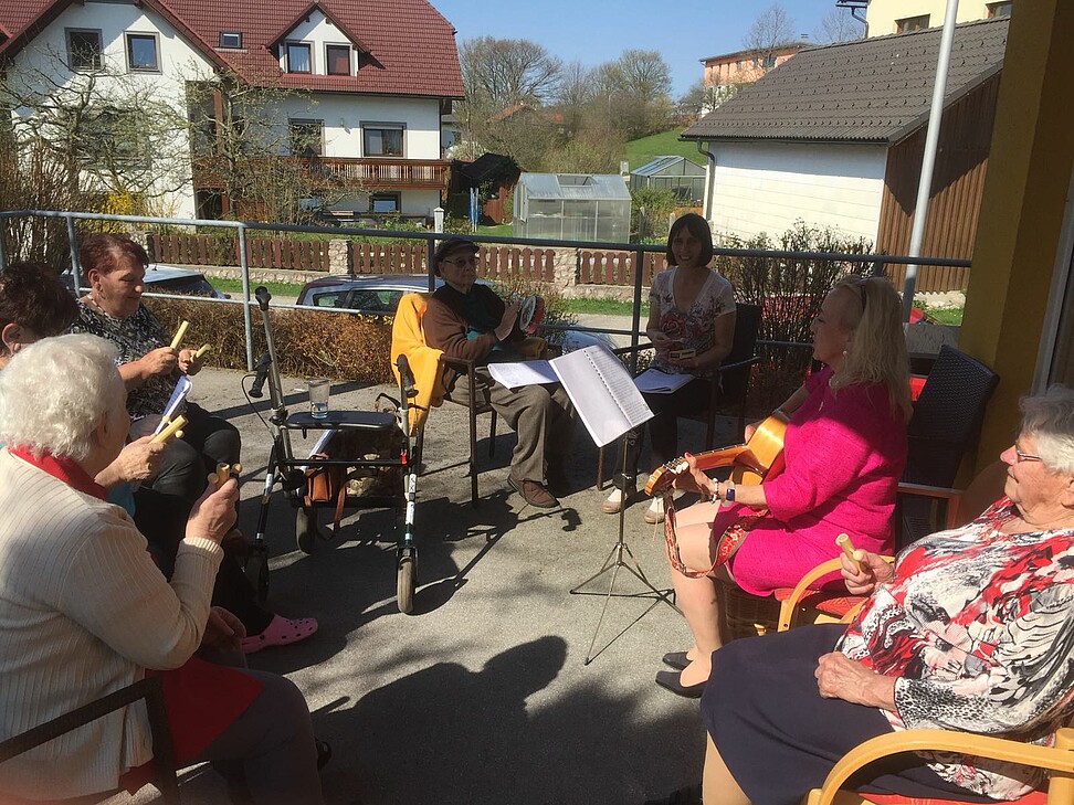 6 Personen sitzen im Kreis zum Singen und Musizieren