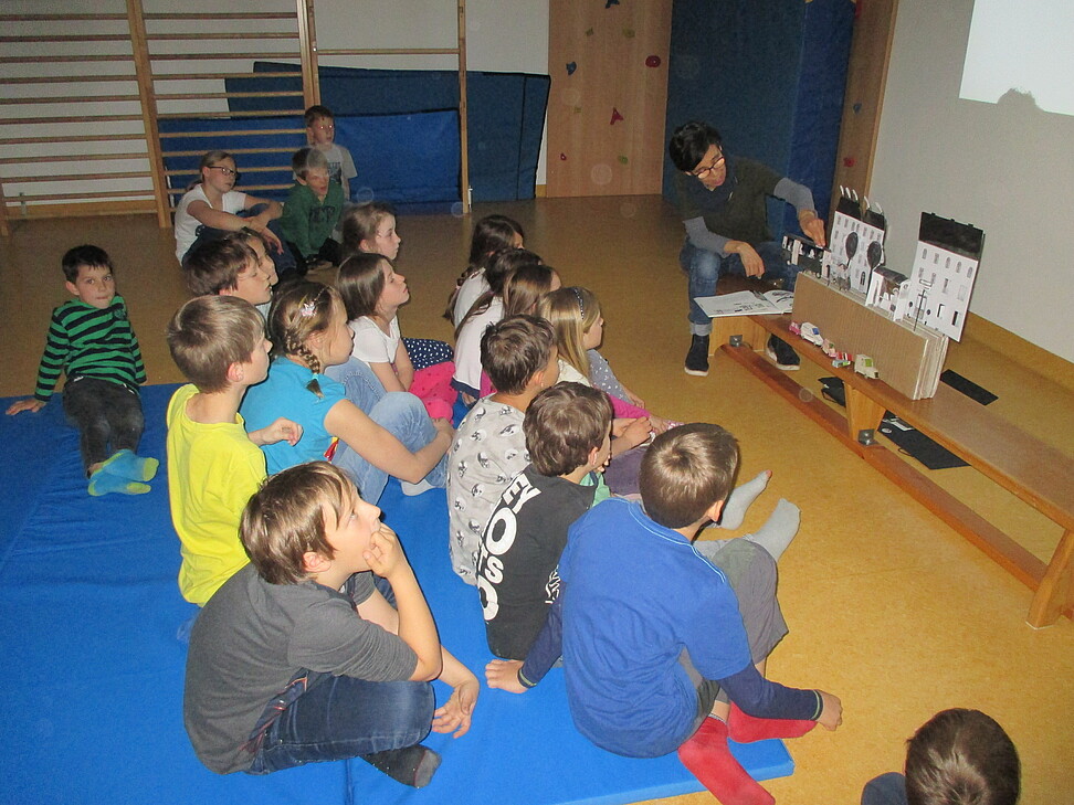 Kinder sitzen und lauschen gespannt dem Vortrag