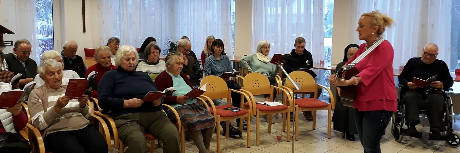 viele Senioren singen Weihnachtslieder mit Gitarrenbegleitung