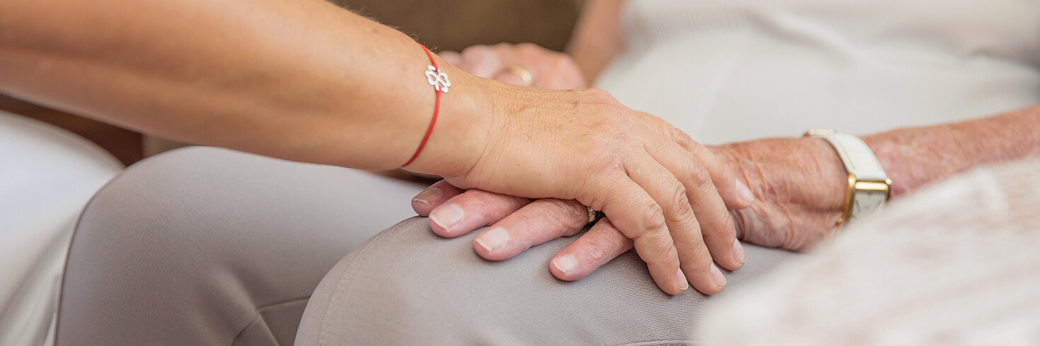 Eine Person legt tröstend oder unterstützend ihre Hand auf die Hand einer anderen Person