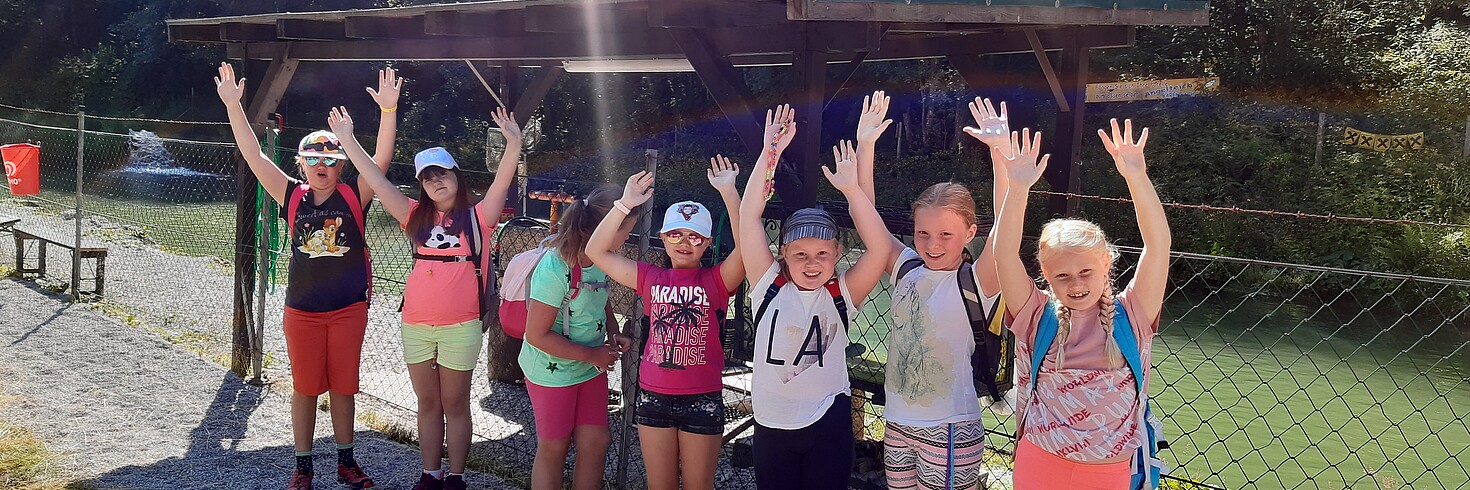 Eine Gruppe Kinder hebt die Hände und jubelt im Freien