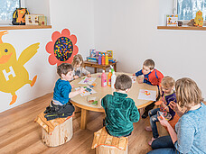 Eine Gruppe Kinder sitzt gemeinsam am Tisch und bastelt