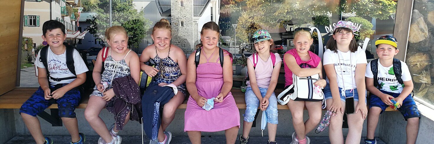 Eine Gruppe Kinder sitzt auf einer Bank im Freien