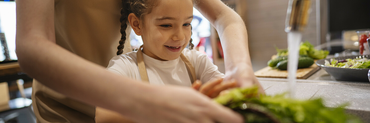 Kochen mit Kindern: Ein Mädchen kocht mit seiner Mutter
