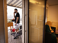Ein Mann steht auf einem Balkon und telefoniert.