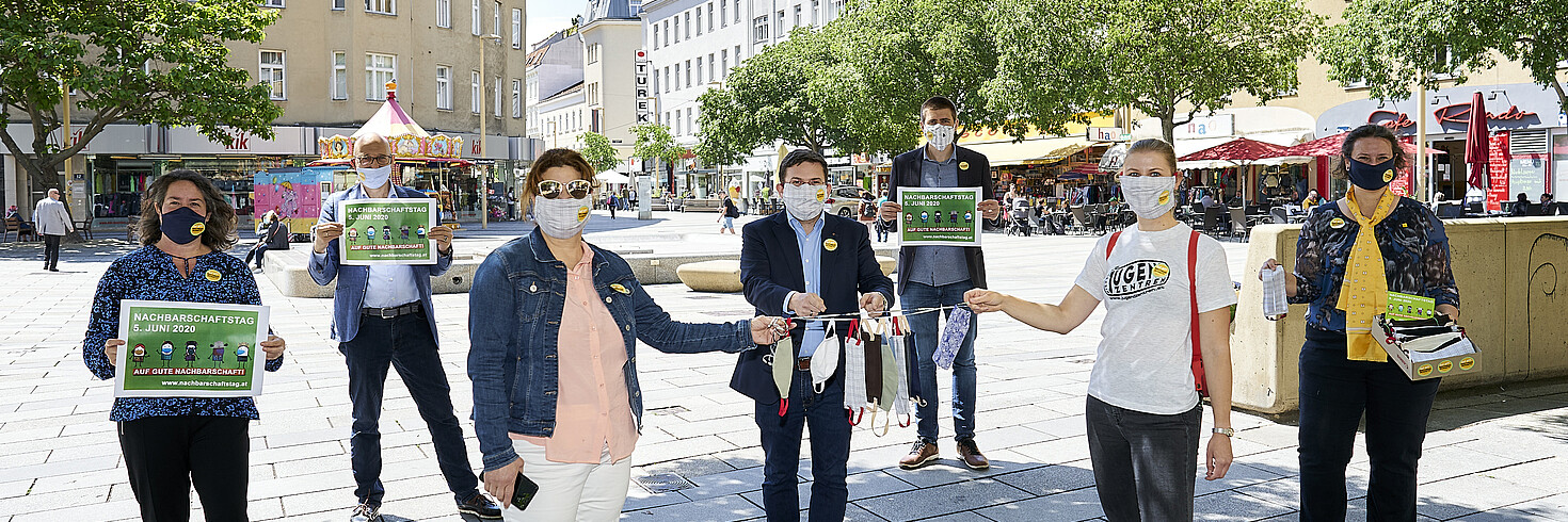 Menschen präsentieren Schutzmasken an einer Schnur