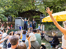 Zwei Personen performen vor einem Publikum auf der Bühne.