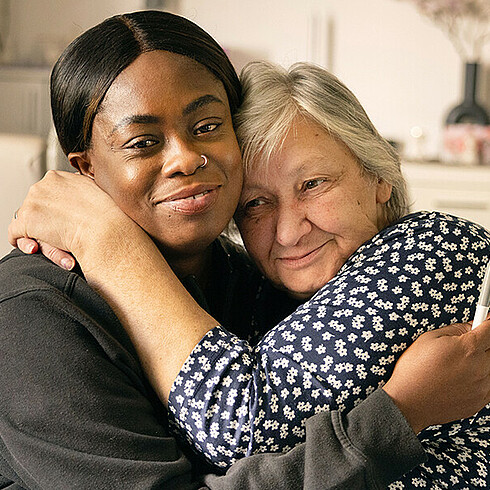 Eine Mitarbeiterin des Wiener Hilfswerks und eine Frau mit weißen Haaren umarmen sich