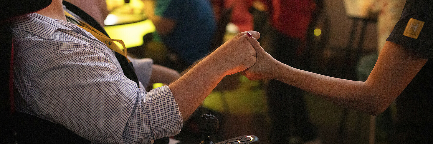 Zwei Menschen halten sich an der Hand.