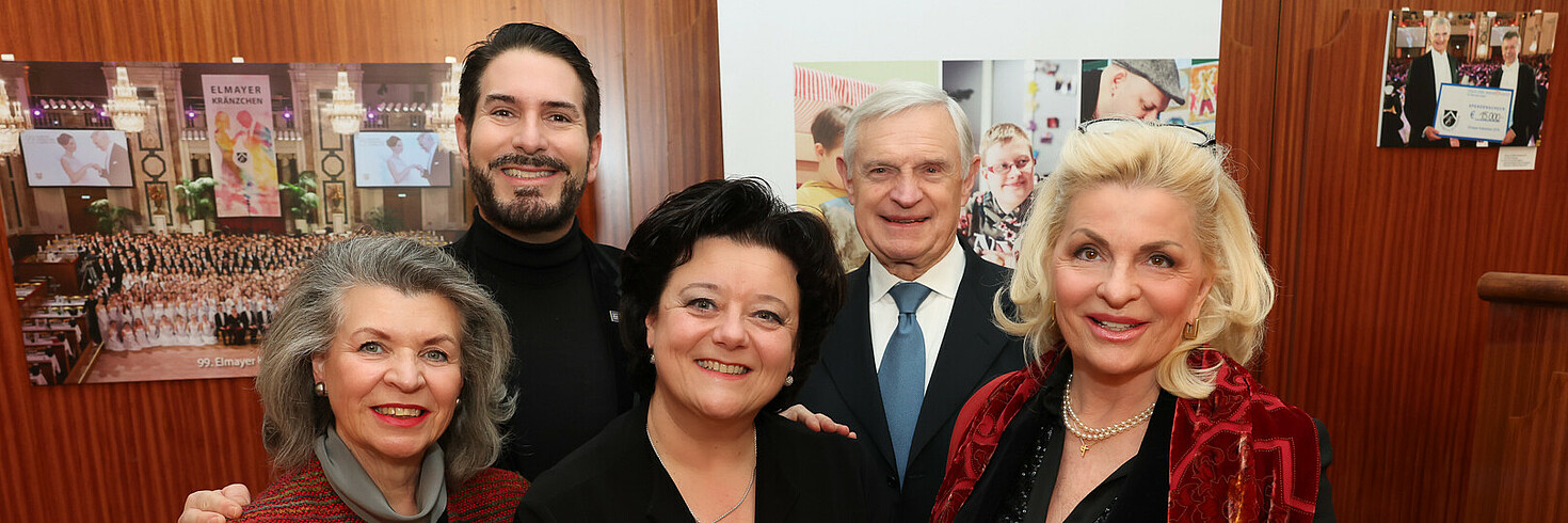 Fünf festlich gekleidete Menschen lächeln in die Kamera.