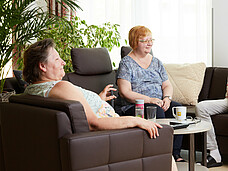 Zwei Frauen sitzen am Sofa und tratschen