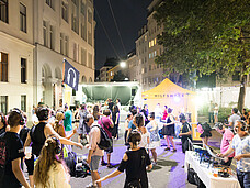 Viele Menschen tanzen mit Kopfhörern auf einem Straßenfest.